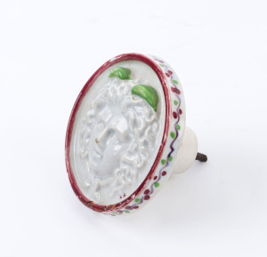 An antique French porcelain furniture knob with Medusa head motif, 18th/19th century, 9.5cm diameter