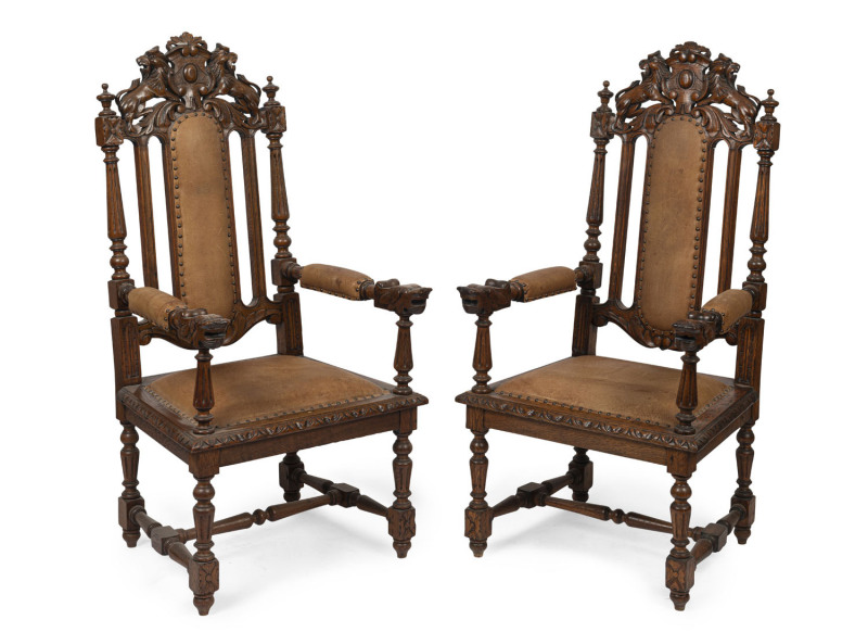 A pair of French carved oak armchairs with brown leather upholstery and rampant lion crests, 19th century, 65cm across the arms