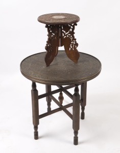 North Indian Islamic decorative circular copper tray table on folding wooden legs, (58cm high, 58cm diameter); also a small table with carved floral design and a central inlay in bone, folding wooden legs, (32cm high, 30cm diameter), early to mid 20th cen