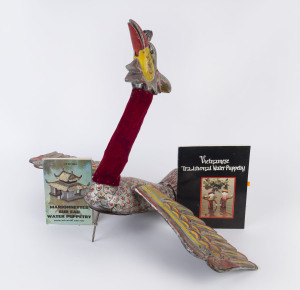 A Vietnamese Water Puppet in the shape of a Phoenix (Phuong), painted wood, wings attached to body with leather straps, red velvet cloth around neck, steel rod 28cm long, wingspan 78cm.