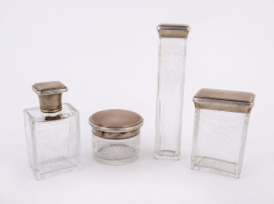 A set of four vanity bottles, wheel cut crystal with sterling silver and enamel lids, interiors with original gilt finish, made in London, circa 1911, the largest 17cm high