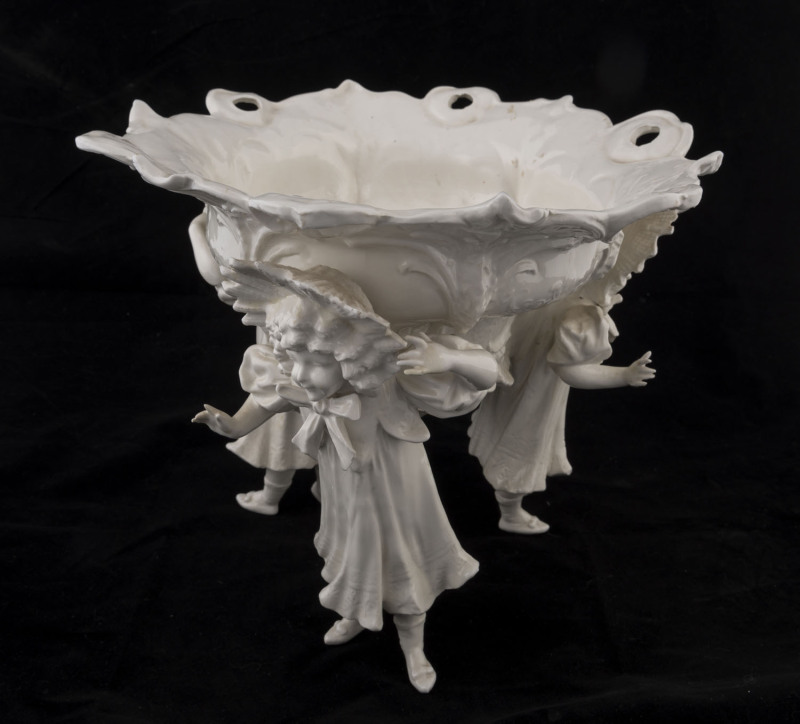 A Continental white porcelain table centrepiece, floral decorated bowl supported by three young female figures, early 20th century, ​factory mark to the base, 25cm high