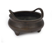 A Chinese cast and patinated bronze censer of squat bowl form with carrying handles, supported on 3 feet, 19th century, impressed mark to the base, 9.5cm high, 16cm diameter