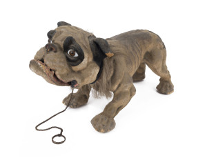 An antique French papier-mâché "GROWLER" bulldog childs pull along toy, 19th century. With nodding head and pull lead mechanism which opens the dog's mouth and growls. In original working condition, with original glass eyes and wooden castor wheels, the l