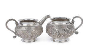 An antique Burmese silver milk jug and sugar basin with fine repoussé decoration, late 19th century, the jug 10cm high, 16cm wide, 510 grams total