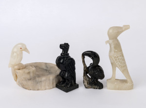 A collection of hard and soft stone bird carvings, consisting of an Alabaster Egyptian style eagle, a marble ashtray with bird resting on a tree log, a hard stone carved pelican and a Native American totem hard stone carved eagle, (4 items) ​the taller 16