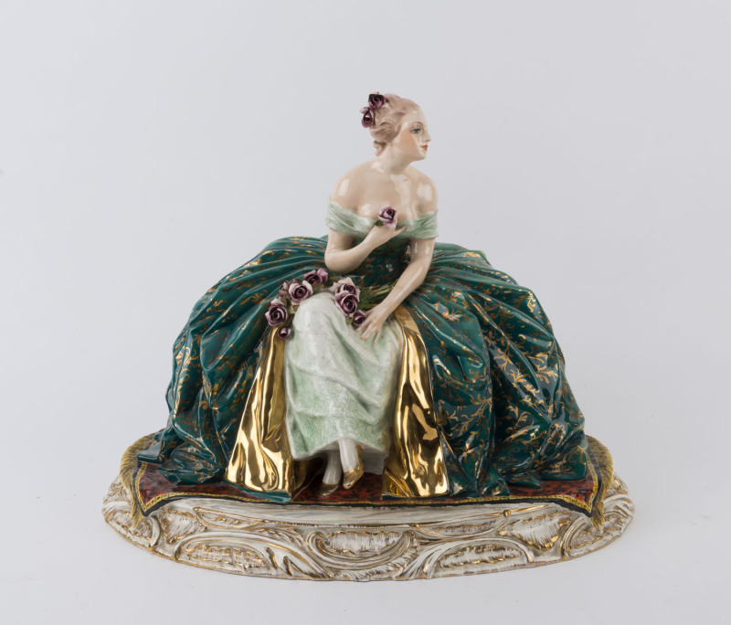 CACCIAPUOTI Italian porcelain statue of a seated lady in ballgown, 20th century, original paper label to base, incised "Guido Cacciapuoti", 34cm high, 43cm wide