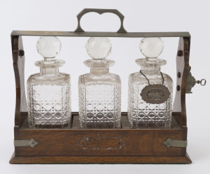 An antique three bottle tantalus with hobnail crystal decanters, late 19th century, 31cm high
