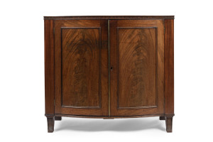 A Georgian bow front two door cabinet with book-matched flame mahogany panels, brass reeded trim and unusual vertical fluted edge, circa 1800, 86cm high, 97cm wide, 54cm deep
