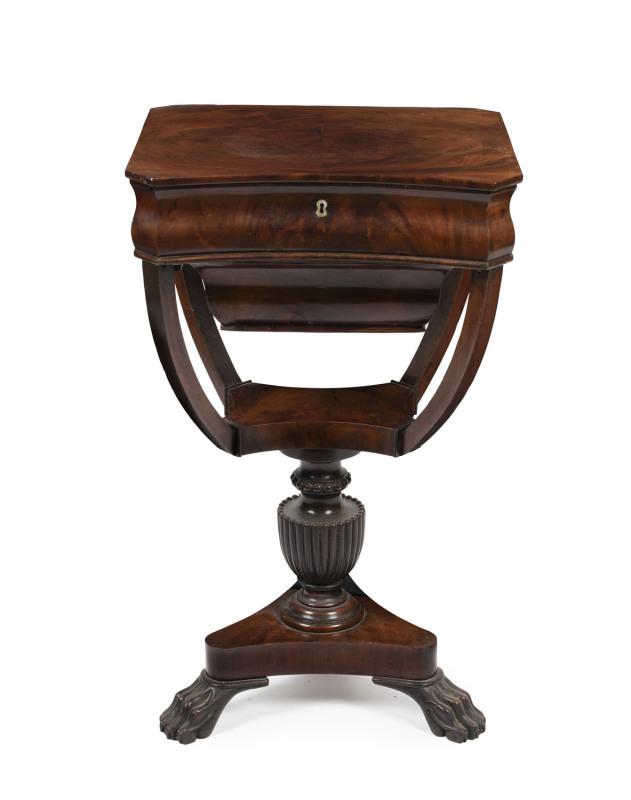 An antique English mahogany work table, lift-top revealing numerous lidded compartments with whale bone handles, finely fluted column and carved claw feet, circa 1830, ​77cm high, 47cm wide, 38cm deep