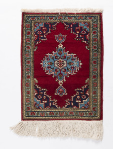 A small Persian hand-knotted wool rug on red ground, 20th century, 85 x 58cm