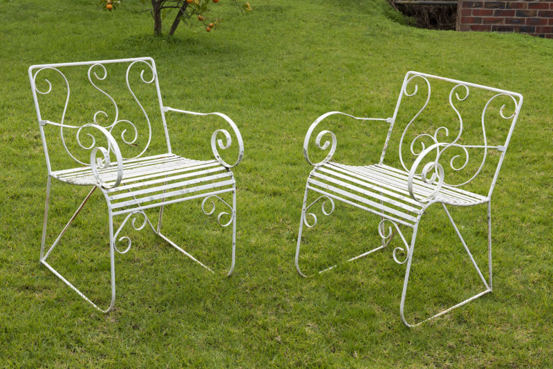 A pair of vintage wrought iron garden chairs with scrolling arms, mid 20th century, 54cm across the arms