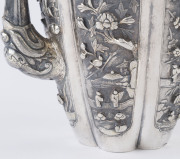An antique Chinese silver teapot adorned with vignettes of country scenes and floral sprays, Foo dog finial with remains of gilt highlights, 19th century, 18cm high, 17cm wide, 565grams - 11