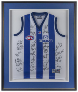 NORTH MELBOURNE: North Melbourne football guernsey signed by the 2004 team, with approximately 30 signatures including including David King, Daniel Wells; high quality 'Artcare Archival System' mounting, framing & glazing; overall 100x83cm.