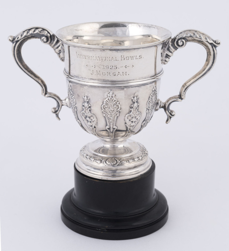 BOWLS: A sterling silver two-handled cup by Fenton Bros., Ltd (Sheffield) with engraved legend "INTERNATIONAL BOWLS. -1925- J. MORGAN" on wooden stand. Overall 14cm high; the cup 10.5cm; 130gms.