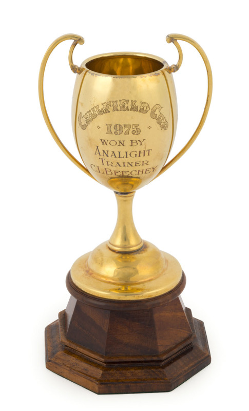 1975 CAULFIELD CUP - WINNER "ANALIGHT": the 9ct gold trainer's trophy, engraved "CAULFIELD CUP 1975 WON BY ANALIGHT : TRAINER C.L. BEECHEY" raised on a custom made wooden plinth. Overall: 16cm high. The Cup: 128gms. Accompanied by the framed winner's phot