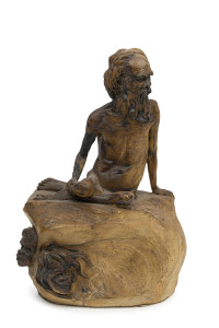 WILLIAM RICKETTS pottery statue of an Aboriginal elder sitting on a rock adorned with three Aboriginal faces, 31cm high 20cm wide