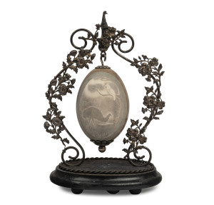 An Australian silver plated emu egg ornament, foliate design with cast emu finial and suspended emu egg carved and decorated with cockatoo and emu in landscape, mounted on ebonised timber plinth, late 19th century, 29cm high. PROVENANCE: Christie's Auctions, Decorative Arts, 2nd, May 1988, lot 173
