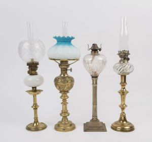 Four candlesticks now converted to kerosene lamps, one with floral decorated pressed brass font, blue and white moulded glass shade, the other three with glass fonts, each with single brass burners, (one chimney missing), 19th century, (4 items), the larg