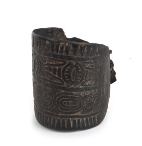 A tribal arm band, carved wood and fibre with remains of natural earth pigments, early 20th century, ​10cm high