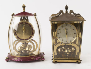 Two SCHATZ German 400 day anniversary clocks, one with silvered dial and Roman numerals housed in a lantern style glazed case; the other with maroon and gilt floral decoration in a domed four glass case, 20th century. the larger 22.5cm high.