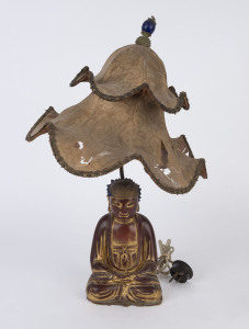 A vintage Chinese table lamp and shade with carved Buddha base and original shade with an antique Mandarin hat button, early 20th century, 51cm high overall