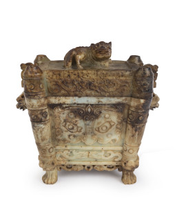A Chinese carved gray jade censer with dark russet inclusions. Adorned with mythical animal face masks, Chi-Long lion cub finial with carved lion feet, Kui dragon handles and archaic Taotie panels, Qing Dynasty 19th/20th century, 21cm high, 22cm wide