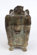 A Chinese carved gray jade censer with dark russet inclusions. Adorned with mythical animal face masks, Chi-Long lion cub finial with carved lion feet, Kui dragon handles and archaic Taotie panels, Qing Dynasty 19th/20th century, 21cm high, 22cm wide - 2