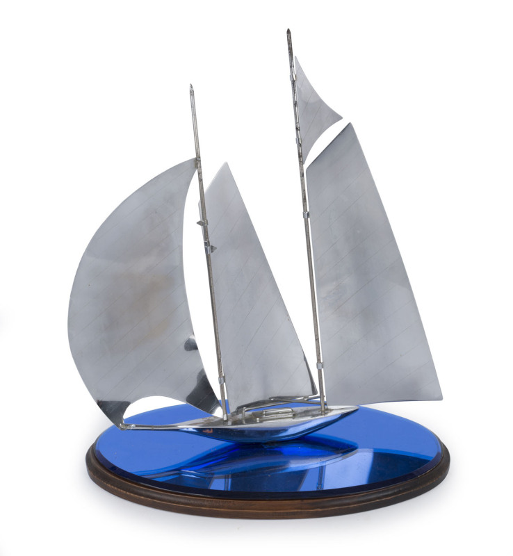 An Art Deco chrome yacht ornament on timber and blue glass base, circa 1930, ​47cm high, 42cm long