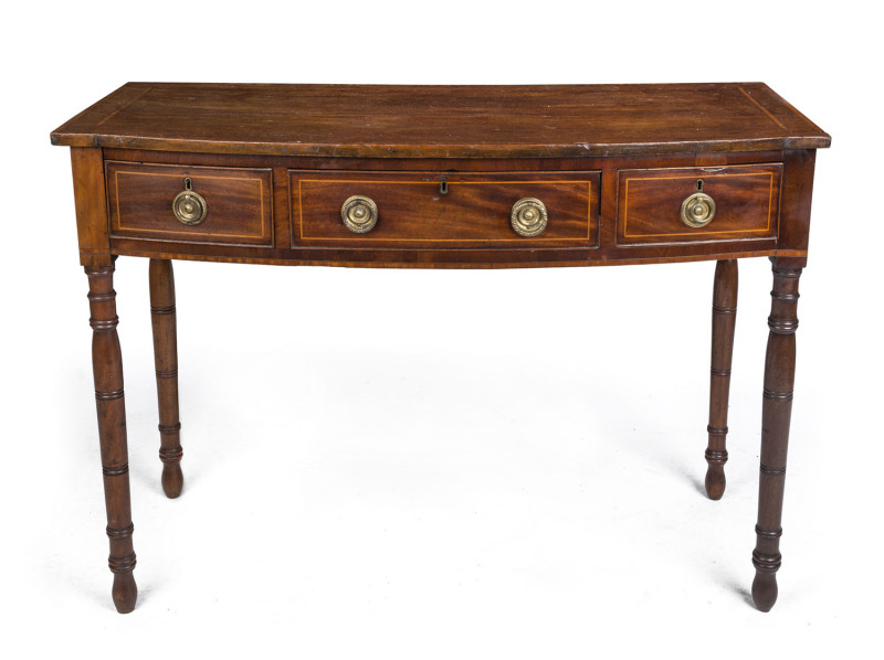 A Georgian bow front three drawer mahogany desk, cross banded in satinwood with cock beading and ring turned legs, early 19th century, ​83cm high, 114cm wide, 51cm deep