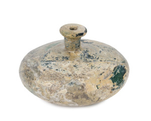 A Sassanian glass bottle, Central Asia, 3rd to 7th century A.D. 8cm high, 13cm diameter. Note: A near identical example is illustrated "Sassanian and Post Sassanian In The Corning Museum Of Glass", page 17.