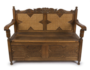 A Tudor revival hall seat, carved oak with caned back and lift-top compartment seat, circa 1920, ​94cm high, 125cm wide, 57cm deep