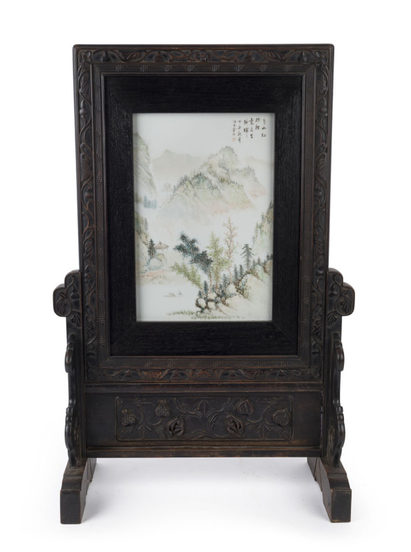 WANG YOUTANG (active 1890-1907), Chinese porcelain table screen in carved wooden stand. The panel decorated with mountain landscape and poem with artist square cartouche in iron red, late Qing Dynasty, 78cm high, 51cm wide, 24cm deep. Note: Illustrated i