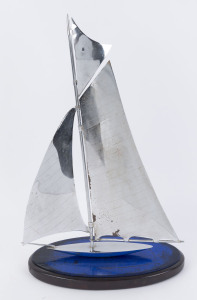 An Art Deco chrome yacht ornament on timber and blue glass base, circa 1930, 51cm high, 31cm long