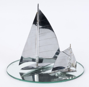 Two chrome yacht ornaments together with an oval mirrored glass base (3 items), circa 1930, the largest 24cm high