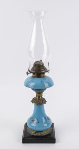 An antique oil lamp with blue glass font and column, single burner, brass collars and black ceramic base, 19th century, ​50cm high