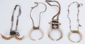 Four tribal necklaces, boar tusk, shell, woven fibre, trade bead and string, Papua New Guinea, ​the largest 19cm wide