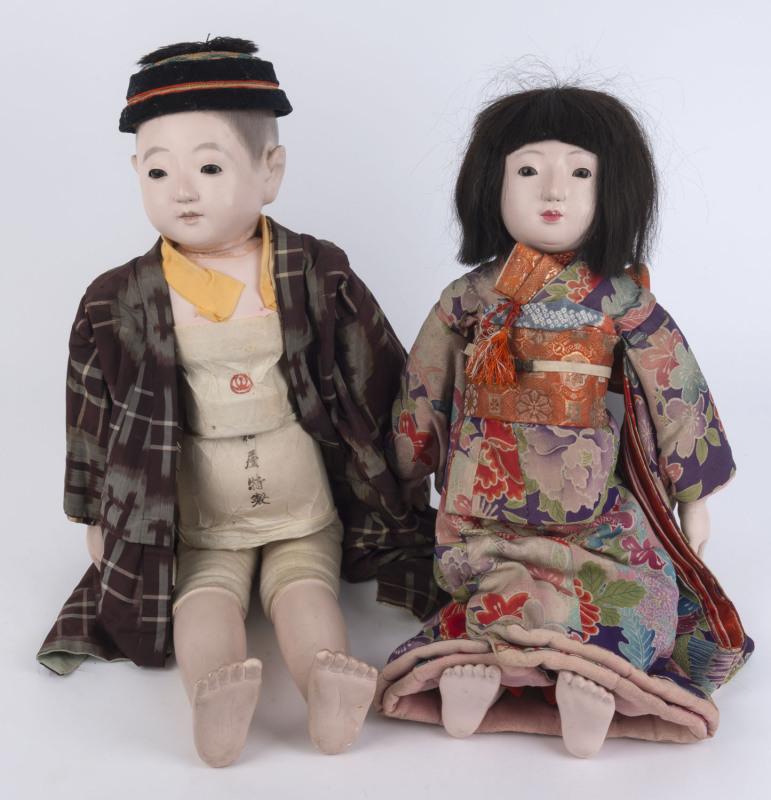 JAPANESE ICHIMATSU DOLLS: male and female dolls in traditional dress with gofun heads, arms and legs, both with inset glass eyes, painted details and hair (on the male figure), the female doll with real hair and wearing floral design kimono, the obi sash