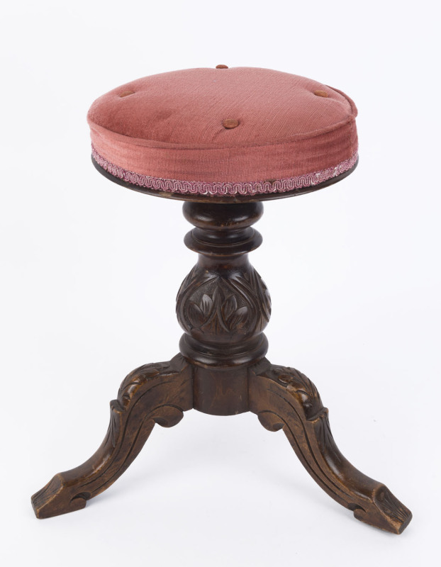 An antique revolving piano stool, carved walnut with dusty pink upholstered top, 19th century, 50cm high, seat 29cm diameter