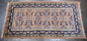 A small Persian hand-knotted wool rug, pink ground with blue border, 160 x 84cm