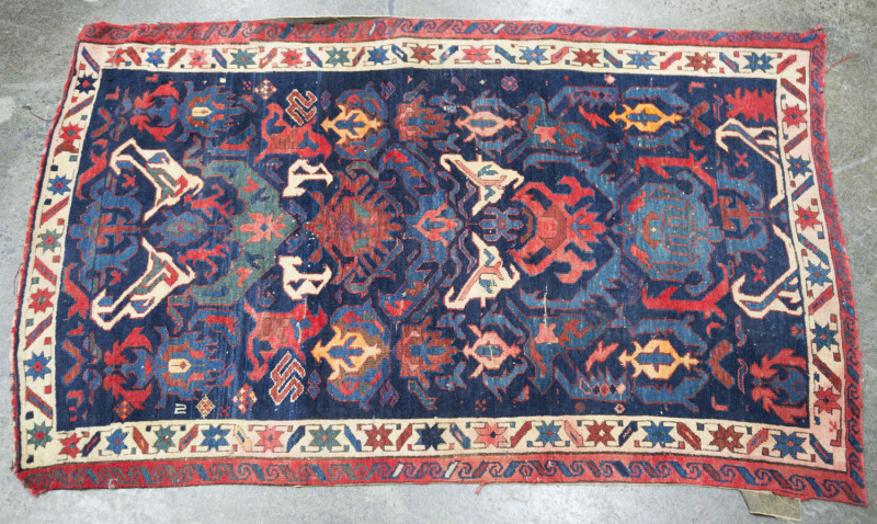 A Persian hand-knotted rug with dark blue ground and red border, ​144 x 90cm