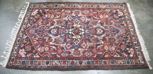 A Persian hand-knotted wool rug with red and blue ground, ​235 x 140cm