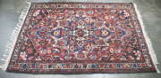 A Persian hand-knotted wool rug with red and blue ground, ​235 x 140cm