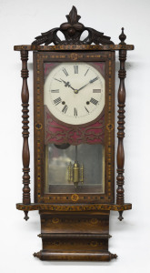 An American wall clock, late 19th century. Walnut and marquetry inlaid case with turned columns flanking a single glassed door with carved pediment decoration, white painted dial with Roman numerals and club style hands. 8 Day time and bell striking sprin