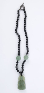 A Chinese green jade Buddha necklace with black glass beads, incised with Wan symbol to back, 42cm long