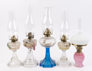 Five assorted kerosene lamps, a pair with moulded glass stands with hand painted floral decoration, one with blue glass moulded base and clear glass font, a single hand-painted moulded glass lamp and a frosted pink glass lamp, all with brass burners and g