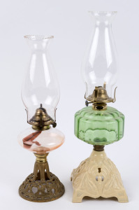 Two kerosene lamps, each with cast metal bases with floral decoration, one with squat clear glass font, the other with a green moulded and reeded glass font, brass single burners and glass chimneys, early 20th century, (2 items), the taller 44cm high