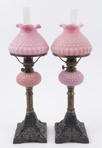 A pair of antique oil lamps with quilted pink glass shades and fonts, single burners on brass and cast metal bases, 19th century, ​51cm high