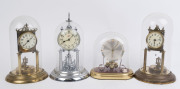 Four German 400 day anniversary clocks, comprising a "SCHATZ" with a nickel plated movement and case under a perspex dome; two other brass cased examples with rotary disk pendulums, each with off white glass dials with Arabic numerals; the fourth with sil