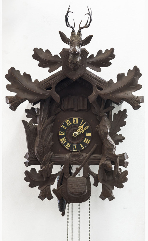 A German Black Forest Cuckoo clock with oakleaf and animal carved case, 20th century. Dial marked "Made in Germany" with twin pinecone weight driven movement, twin bellows, music box and automata cuckoo and huntsman. 52cm high.